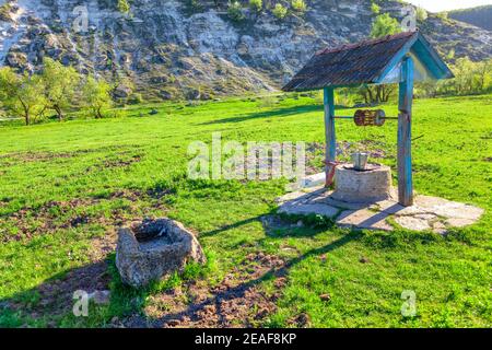 Alter Brunnen auf der Wiese. Wasser gut auf dem Land in schönen Frühling Natur Stockfoto