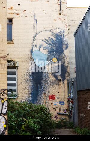 'The Girl with the Pierced Eardrum' Banksy malte einen Verbündeten in Bristol, England. Das Mädchen trägt eine Gesichtsmaske während der Covid Pandemie von 202 Stockfoto