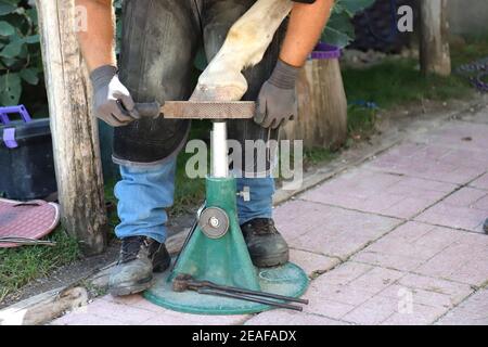 Unbekannter Schmied, der im Sommer mit einem Hufeisen im Freien arbeitet Stockfoto