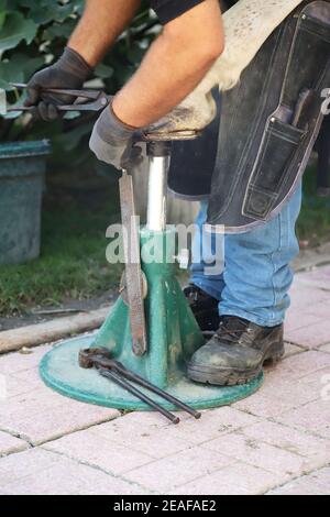 Unbekannter Schmied, der im Sommer mit einem Hufeisen im Freien arbeitet Stockfoto