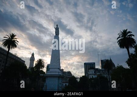 Silhouette von Maipyramide und Palmen gegen Sonnenuntergang Himmel auf der Plaza de Mayo in Buenos Aires, Argentinien. Das Piramide de Mayo Denkmal Stockfoto