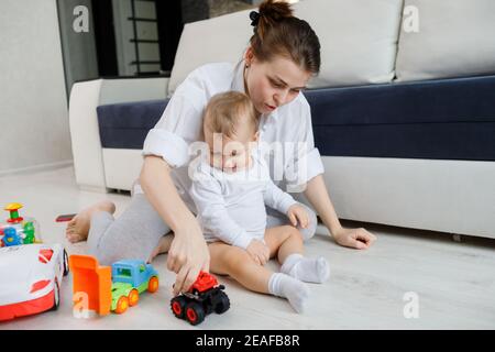 Junge Mutter und kleines Kind spielt mit Spielzeug sitzen auf Boden Stockfoto