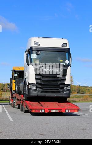 Fahrzeugträger mit zwei neuen Scania-Lkw, weiß R650 und gelb R650 XT, geparkt auf LKW-Halteplatz. Vertikale Ansicht. Salo, Finnland. 5. Oktober 201 Stockfoto