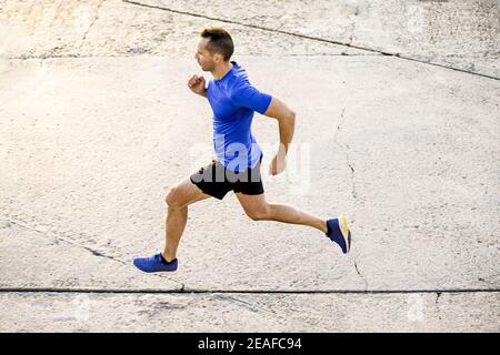 Männlicher Athlet Läufer laufen auf Betonstraße Stockfoto