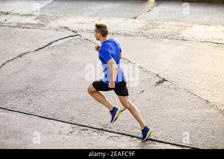 Männlicher Läufer, um am Morgen joggen entlang einer Betonstraße laufen Stockfoto