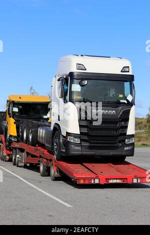 Fahrzeugträger mit zwei neuen Scania-Lkw, weiß R650 und gelb R650 XT, geparkt auf LKW-Halteplatz. Vertikale Ansicht. Salo, Finnland. 5. Oktober 201 Stockfoto