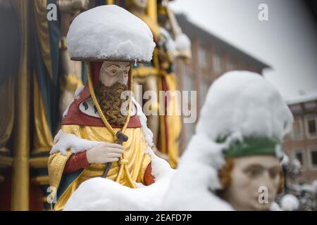 Nürnberg, Deutschland. Februar 2021, 09th. Die Figuren auf dem "schönen Brunnen" auf dem Hauptmarkt in der Altstadt sind mit Schnee bedeckt. Die Figuren sollen die Weltanschauung des Heiligen Römischen Reiches im Mittelalter darstellen. Der schöne Brunnen wurde auf Wunsch von Kaiser Karl IV. Im letzten Jahrzehnt des 14th. Jahrhunderts erbaut. Quelle: Daniel Karmann/dpa/Alamy Live News Stockfoto