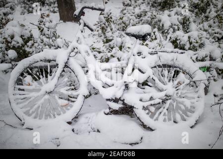 Nürnberg, Deutschland. Februar 2021, 09th. Ein komplett eingeschneit Fahrrad liegt an einer Stange gelehnt. Quelle: Daniel Karmann/dpa/Alamy Live News Stockfoto