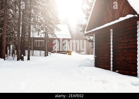Holzhaus zwischen Bäumen im Winterwald. Blockhütte. Gehäuse aus natürlichen Baustoffen. Umweltfreundliche Konstruktion. Stockfoto
