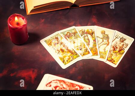 Blick von oben auf Tarot-Karten mit Kerzenlicht und Buch auf den dunklen Hintergrund, Halloween und zukünftige Lesekonzept. Stockfoto