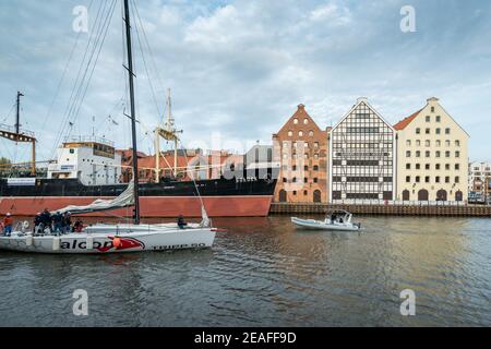 Danzig, Polen - 05,06.2017: Menschen auf einer kleinen Sportyacht, die aus einem Kanal in Danzig, Polen, in die Ostsee segelt. Größeres Schiff und traditionell Stockfoto