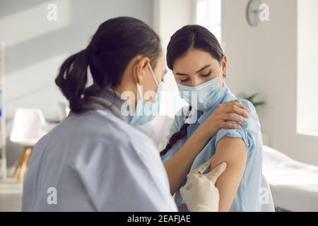 Junge Frau erhält während der saisonalen Impfkampagne eine antivirale Impfstoffinjektion Stockfoto