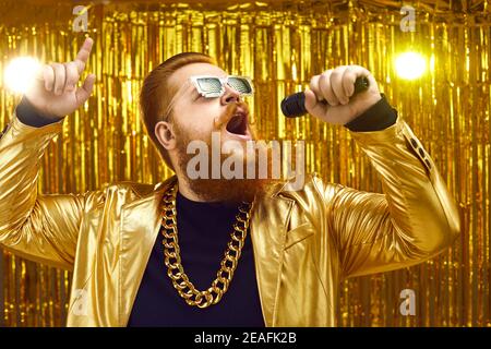 Sänger in extravaganter glänzender Jacke mit Mikrofon und singenden Songs Beim Konzert Stockfoto