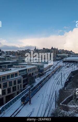 Blick auf einen Zug, der den Bahnhof Waverley in Edinburgh verlässt Nach einem Schneesturm Stockfoto