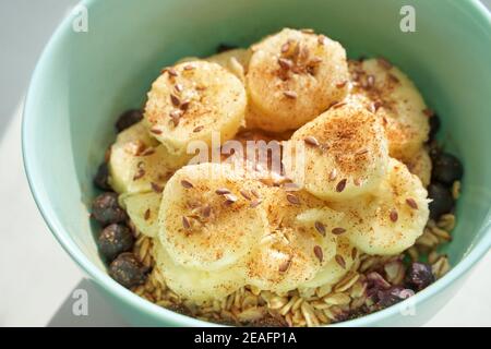Gesundes Frühstück. Haferflocken mit Banane und Leinsamen in der Schüssel. Stockfoto