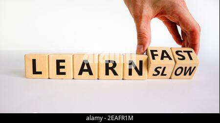 Lernen Sie langsam oder schnell Symbol. Geschäftsmann dreht Holzwürfel und ändert die Worte "langsam lernen" zu "schnell lernen". Schöner weißer Hintergrund, Kopierbereich. Busi Stockfoto