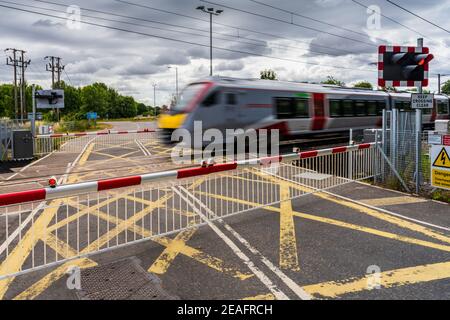 Level Crossing UK - Greater Anglia Stadler Bi-Mode FLIRT-Zug fährt durch eine Bahnüberfahrt in South Cambridgeshire. Stockfoto