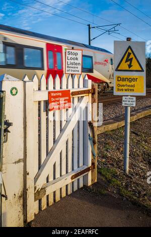 Fußgängerzug Crossing Gate mit Passing Greater Anglia Zug - nicht automatisierte Bahnübergang für Fußgänger mit Warnschildern. Stockfoto