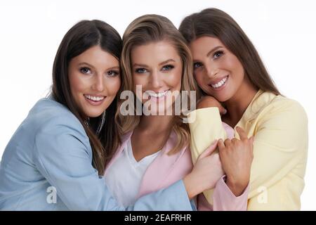 Drei Frauen in Pastellanzügen posieren auf weißem Hintergrund Stockfoto