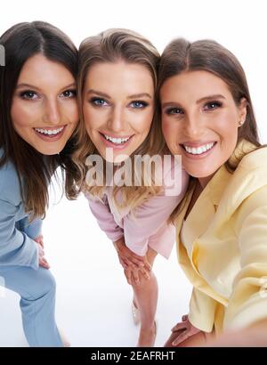 Drei Frauen in Pastellanzügen posieren auf weißem Hintergrund Stockfoto