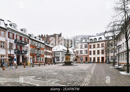 Heidelberg, Deutschland - Februar 2020: Kornmarkt in der Altstadt mit Brunnen und Blick auf das historische Heidelberger Schloss mit Schneedauer Stockfoto