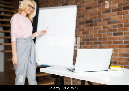 Reife Lehrerin, Tutor Coach in Brille mit blonden Haaren Blick auf den Laptop-Bildschirm, geben virtuellen Unterricht online per Zoom Konferenzgespräch, oder Stockfoto