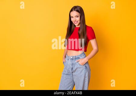 Attraktive Dame gute Laune tragen lässige rote Crop Top Jeans Stehen über gelben Hintergrund lebendige Farbe Stockfoto