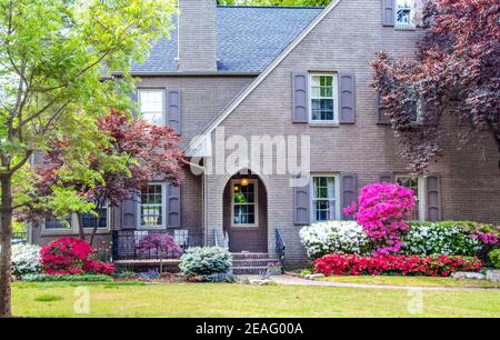 Eingang zum zweistöckigen grauen Backsteinhaus mit japanischer Landschaft Ahornbäume und Azaleen mit Fensterläden und einem vorderen Sitzbereich Stockfoto