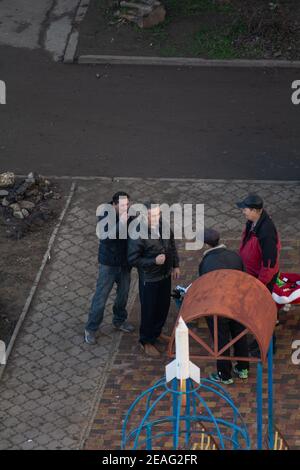 Tiraspol, Moldawien - 1. Januar 2021: Ein als Weihnachtsmann gekleideter Mann und eine Gruppe von Männern, die am ersten Neujahrstag 2 Alkohol auf dem Spielplatz trinken Stockfoto