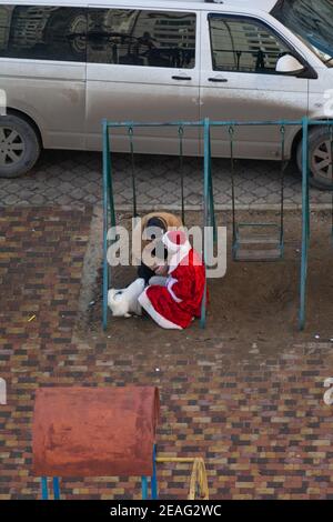 Tiraspol, Moldawien - 1. Januar 2021: Ein betrunkener Mann sitzt auf einer Kinderschaukel und hat einen Dialog mit einem betrunkenen Mann in einem Weihnachtsmann-Kostüm Stockfoto