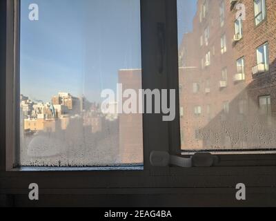 Kalte Zimmereinrichtung mit Blick auf Kondenswasser, das sich im frühen Winter an den Innenfenstern gebildet hat. Kondensation ist dafür bekannt, dass sie Feuchtigkeit und Schimmel verursacht Stockfoto