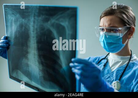 Frau GP Arzt hält Brust Röntgenfilm Scan, medizinische Frau Arbeiter Untersuchung der Lunge des Patienten während einer schweren akuten Atemwegserkrankung des Coronavirus Stockfoto