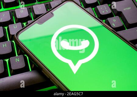 Mobiltelefon mit grünem whatsapp-Logo auf dem Display und bunt beleuchteter Tastatur aus nächster Nähe. Smartphone-Konzept mit der Messaging-Anwendung mit t Stockfoto