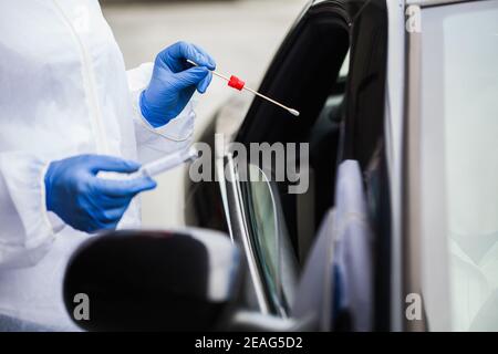 Medizinisches Personal in N95 PSA Durchführung Nasen-und Rachenabstrich Auf Person im Fahrzeug durch Autofenster, COVID-19 UK NHS mobil Testcenter Drive-Thru Stockfoto