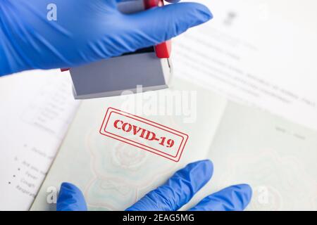 Britischer Grenzschutzbeamter mit blauem Schutzhandschuh und Stempel COVID-19 Auf Dokument, Gesundheitspass oder Immunität Pass, risikofreie Zertifikat-ID Stockfoto