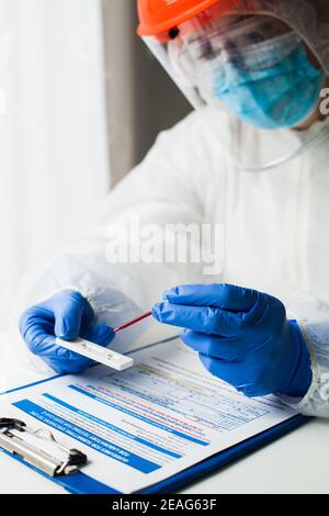 Labortechniker Medizintechniker, der Coronavirus COVID-19 Schnelldiagnosetest auf Antikörper durchführt, tragen persönliche Schutzausrüstung PSA Stockfoto