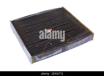 Schmutziger Kabinenluftfilter in einem Winkel mit getrockneten Blättern und schmutziger Seitenansicht isoliert auf weißem Hintergrund. Stockfoto
