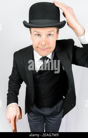 Portrait of man in Dark Suit mit Bowler Hut und Regenschirm. Klassischer und exzentrischer englischer Gentleman. Britischer Geschäftsmann oder Butler. Stockfoto