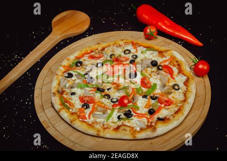 Vegetarische Pizza mit Gemüse auf Holzplatte. Promotion Pizza Hintergrund. Stockfoto