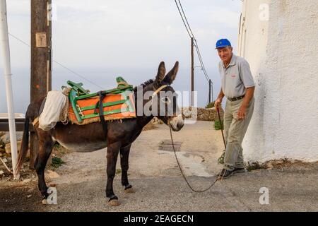 Folegandros, Griechenland - 24. September 2020: Griechischer Mann und sein Esel auf der Straße im Dorf Chora auf der Insel Folegandros. Stockfoto