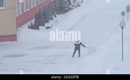 Eine Person entfernt im Winter Schnee in einem Schneesturm, arbeitet mit einer Schaufel Stockfoto