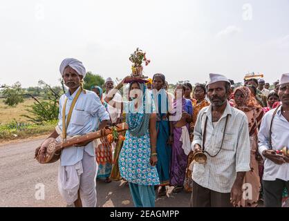 Jamunai, Karnataka, Indien - 8. November 2013: Nahaufnahme der Pilgergruppe, die zum Krishna-Tempel in Pandrapura unter silbernem Himmel mit grünem Laub marschiert Stockfoto