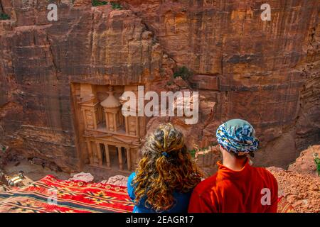 Junges Paar sitzt an einem Aussichtspunkt auf Al Khazneh Grab auch Schatzkammer in Petra, Jordanien genannt Stockfoto