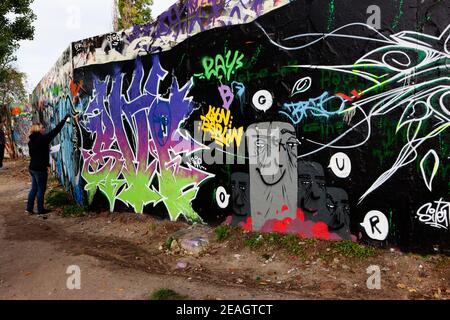 Berlin, Deutschland Besucher sprühen Graffiti an eine Wand im Mauerpark, in der Nähe der ehemaligen Mauer. Stockfoto