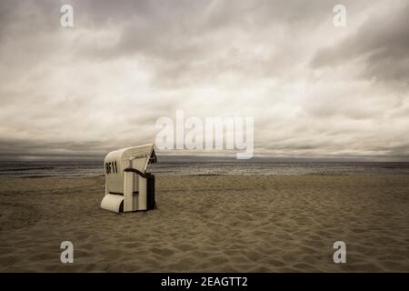 Urlaub Nostalgie und ferne Erinnerungen Konzept Aufnahme eines Strandes Szene mit einem Strandkorb und dramatischem Himmel in Sepia Stockfoto