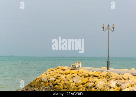 Eine leere Bank und eine Straßenlaterne auf einem Pier in Kuwait. Stockfoto