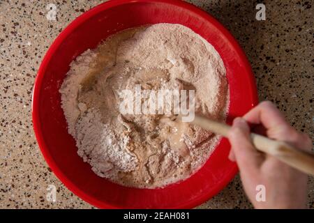 Wasser wird in eine Schüssel mit Mehl, Hefe und Salz gegeben. Serie Schritt-für-Schritt Herstellung hausgemachtes Brot. Bild 2 von 13 Stockfoto