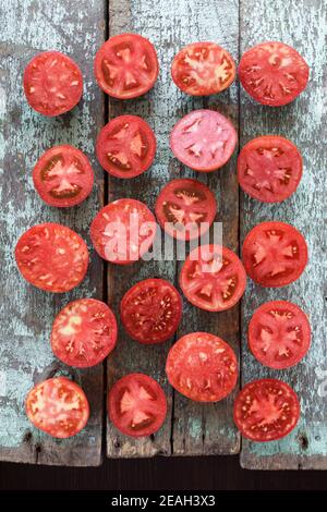 Bio-Lebensmittel. Hausgemachten Erbstück Tomaten in Hälften geschnitten auf alten schäbigen blauen Brettern Overhead Ansicht Stockfoto