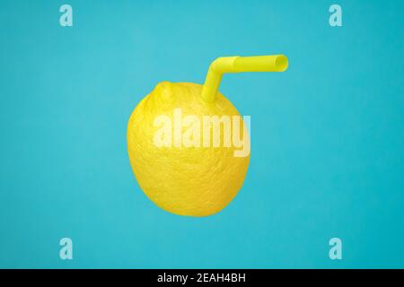 Reife, saftige Zitrone als Getränk im Glas mit Stroh oder natürliche, frische Limonade mit echten Früchten auf Blau. Vitamin C in gelben Zitronenfrüchten minimal Stockfoto