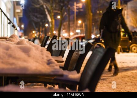 Berlin, Deutschland. Februar 2021, 09th. Tische und Stühle stehen vor einem geschlossenen Café und sind mit Schnee bedeckt. Eine Person geht daran vorbei. Quelle: Kira Hofmann/dpa-Zentralbild/dpa/Alamy Live News Stockfoto